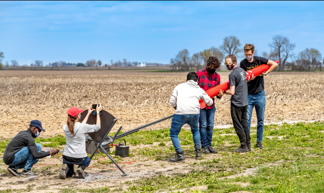 Team working on rocket in field
